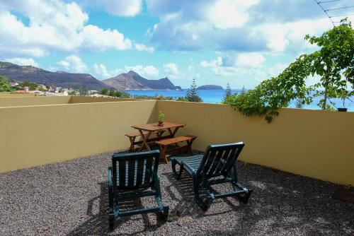 duas cadeiras e uma mesa em frente a uma parede em Bela Vista Capazi em Porto Santo