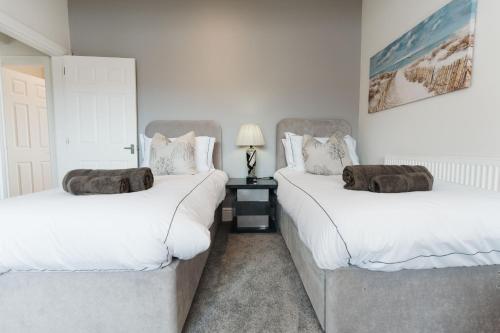 two twin beds in a room with white walls at Birkby Lodge Escape in Lytham St Annes
