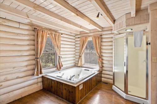 eine Badewanne in einem Zimmer mit Holzwänden und Fenstern in der Unterkunft Shadyview Ridge #104 in Sevierville