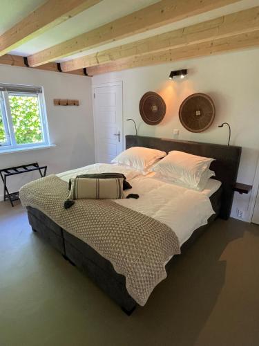 a bedroom with a large bed with white sheets at Bed & Breakfast Zeeuws Gelukkig in Serooskerke