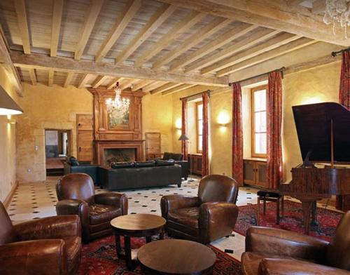a living room with leather furniture and a grand piano at Sarrasins Bed and Breakfast in Beynac-et-Cazenac