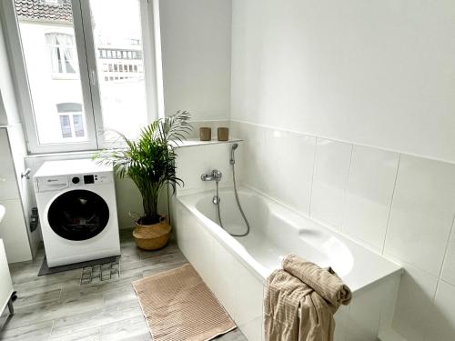 a white bathroom with a tub and a washing machine at Design Apartment - Parking - Kingsize-Bett - 2x Bad - Zentrum in Hannover