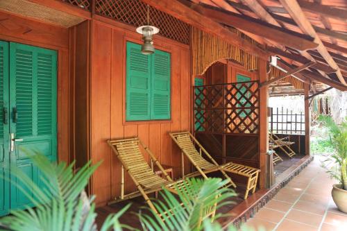 a house with green doors and chairs on the porch at Vamxang Rustic Home in Can Tho