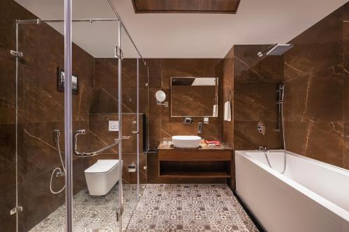 a bathroom with a shower and a sink and a tub at WelcomHeritage Grand, Srinagar in Srinagar