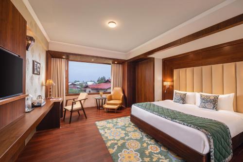 a hotel room with a bed and a television at WelcomHeritage Grand, Srinagar in Srinagar