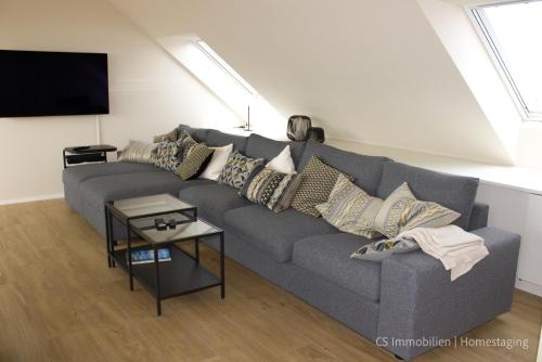 a living room with a gray couch with pillows at Designerloft See in Immenstaad am Bodensee