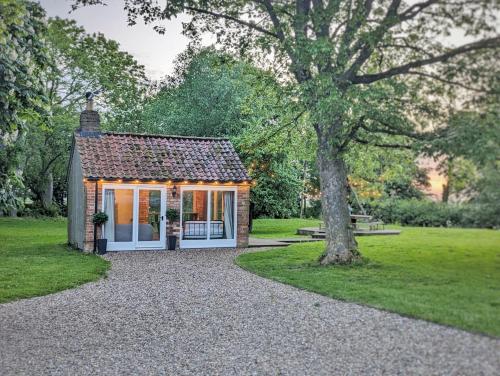 a small cottage in a park with a tree at The Old Forge in Bishop Wilton