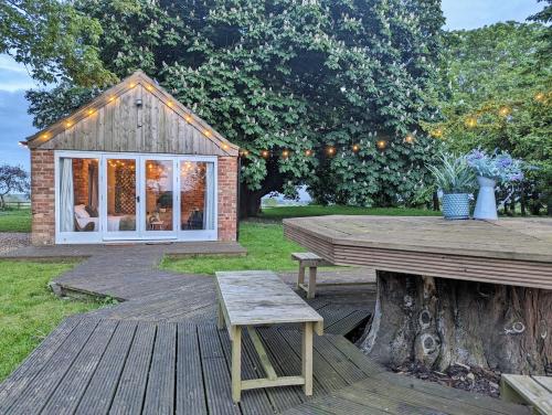 a wooden deck with a picnic table and a house at The Old Forge in Bishop Wilton