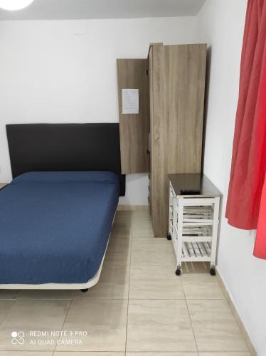 um pequeno quarto com uma cama e uma mesa de cabeceira em Alojamientos Playa Centro Corralejo 9 em Corralejo