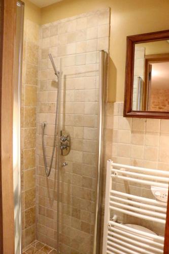 a shower with a glass door in a bathroom at Les Perroutis in Saint-Alvère