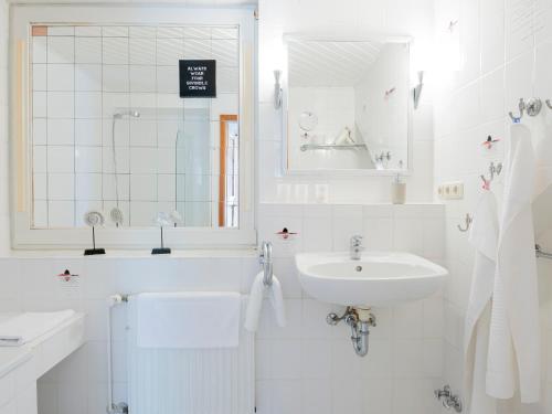 a white bathroom with a sink and a mirror at Lieblingsort Freude in Timmendorfer Strand