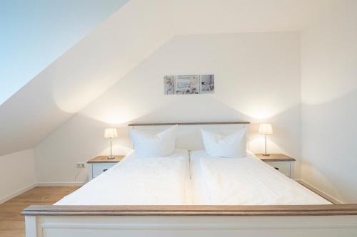 a bedroom with a white bed with two lamps at Lieblingsort Dankbarkeit in Timmendorfer Strand