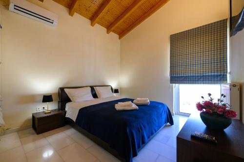 a bedroom with a bed with blue sheets and a window at Kalamata Panorama Villa in Kalamata