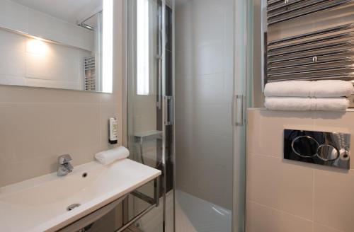 uma casa de banho com um lavatório e um chuveiro em Kyriad Lyon Est - Bron Eurexpo Le Cottage em Bron