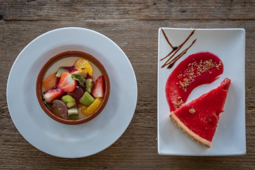 a plate with a bowl of fruit salad and a piece of cake at Kyriad Lyon Est - Bron Eurexpo Le Cottage in Bron