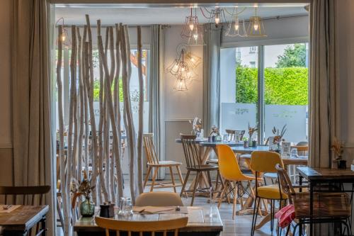 a restaurant with tables and chairs and windows at Kyriad Lyon Est - Bron Eurexpo Le Cottage in Bron