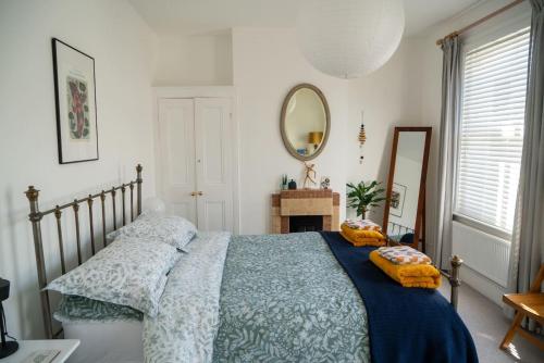 a bedroom with a bed with a blue blanket and a mirror at Stylish two bedroom terrace with garden in Ramsgate