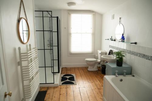 a bathroom with a tub and a toilet and a sink at Stylish two bedroom terrace with garden in Ramsgate
