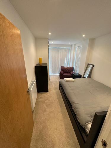 a bedroom with a bed and a chair and a door at Colindale luxury Apartment in Colindale