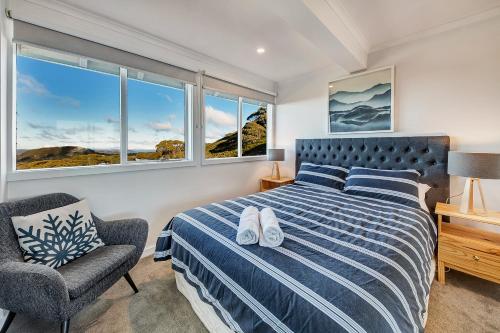 a bedroom with a bed and a chair and windows at The Penthouse @ Alpine Haven in Mount Hotham