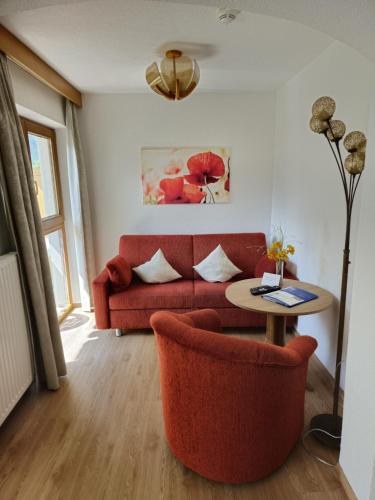 a living room with a red couch and a table at Pension Grein in Pfunds