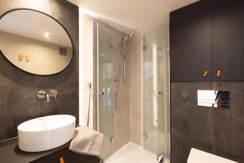 een badkamer met een wastafel en een douche met een spiegel bij Les Dômes des Gorges in Ruoms