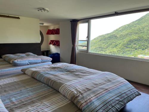two beds in a room with a large window at Slowly B&B in Jiufen