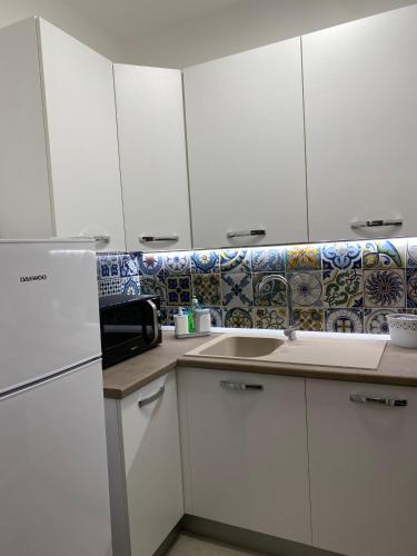 a white kitchen with white cabinets and a sink at IL FICUS - HOLIDAYS HOME in Mazara del Vallo