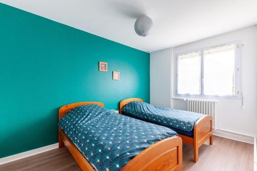 2 camas en una habitación con una pared verde en Gîte Renardeau - Maison à deux pas du centre ville en Carentan