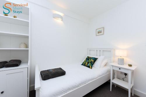 a bedroom with a white bed and a white desk at Two bedroom ground floor apartment near the beach in Margate