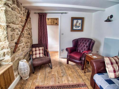 a living room with two chairs and a stone wall at Knocker Cottage is a 3 bedroom made up of 1 double bedroom and 2 small double bedrooms in small village 10 min to beaches in Camborne