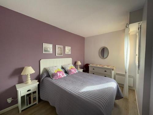 une chambre avec un grand lit aux murs violets dans l'établissement Charmant appartement à 50m de la plage avec terrasse, parking privé et balcon aménagé - FR-1-413-216, à Capbreton