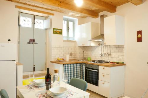 a kitchen with white cabinets and a table with a bottle of wine at Relax & Peace in the Historic Center by Host Hero in Lapedona