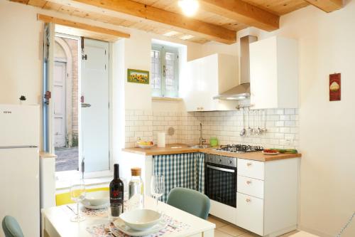 a kitchen with white cabinets and a table with chairs at Relax & Peace in the Historic Center by Host Hero in Lapedona