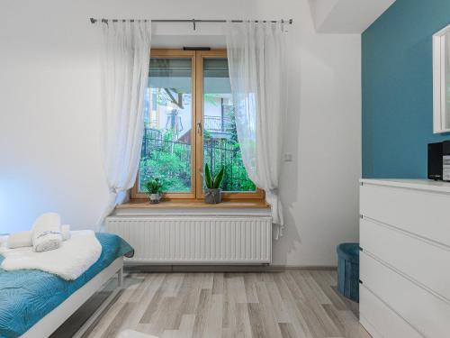 ザコパネにあるVisitZakopane - Aquapark Residence One Apartmentのベッドルーム1室(窓、青い壁のベッド1台付)