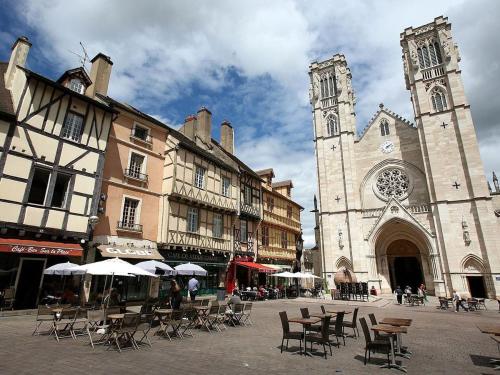 a building with a church with tables and chairs in front of it at NUITS D'HERMES & Spa in Chalon-sur-Saône