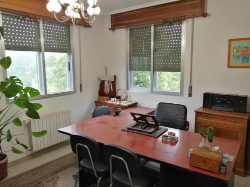 una oficina con mesa de madera, sillas y ventanas en A CASA DOS AVÓS, en Celanova