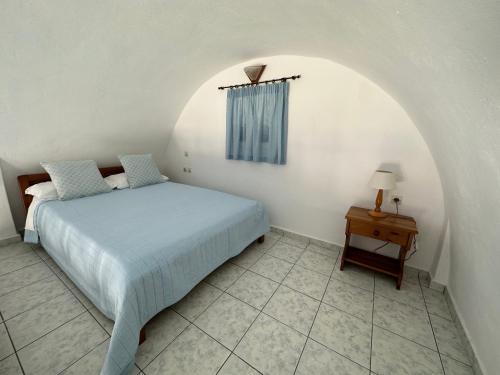 a bedroom with a bed and a table with a lamp at Hotel Paradisos Oia in Oia