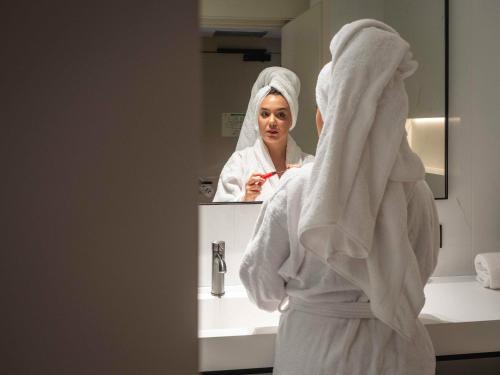 a woman standing in front of a bathroom mirror at ARCELON HOTEL - From 2023 in Barcelona