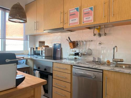 une cuisine avec des armoires en bois et des appareils en acier inoxydable dans l'établissement Lisbon, renovated T2 apartment Portas de Benfica, à Amadora