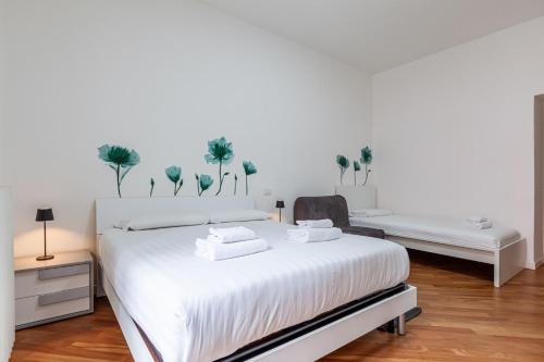 a white bedroom with a large white bed and a chair at Easylife - Oasi urbana in zona Bocconi in Milan