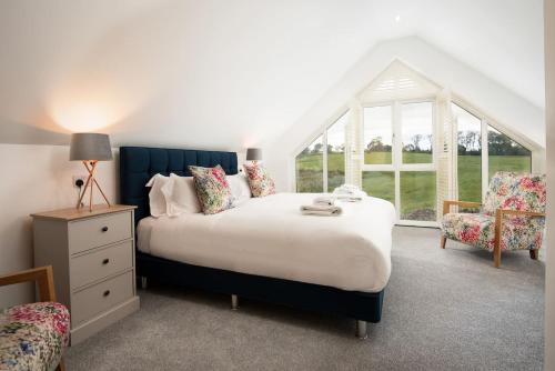 een slaapkamer met een groot bed en een raam bij Sunset View, Hot Tub Haven for max 8 people in Chatton