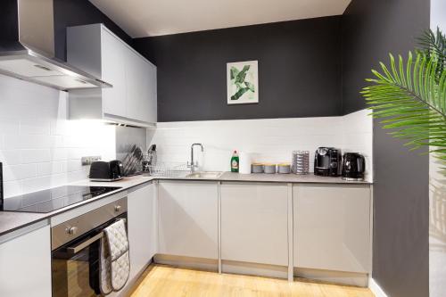 a kitchen with white cabinets and a black wall at At the level - (2 bed flat) in Brighton & Hove