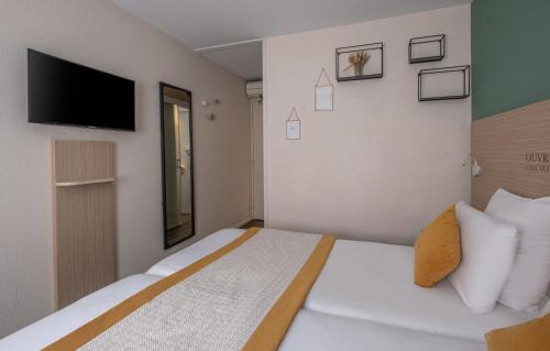 a bedroom with a bed with a tv on the wall at Kyriad Lyon Est - Bron Eurexpo Le Cottage in Bron
