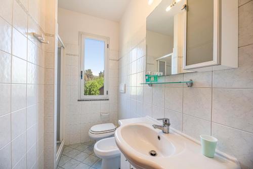 een witte badkamer met een wastafel en een toilet bij Appartamenti Casa Dini in Marina di Campo