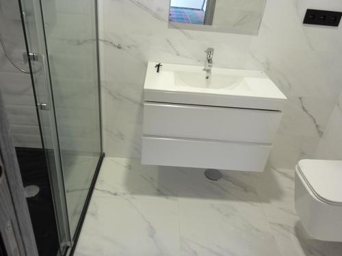 y baño blanco con lavabo y ducha. en Casa San Miguel 93 santander, en Santander