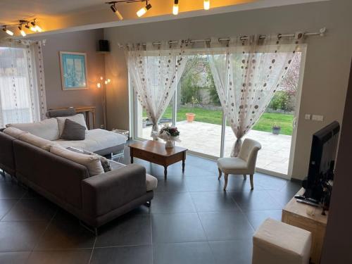 un salon avec un canapé et une grande fenêtre dans l'établissement Villa contemporaine à 2 kms de Chartres, à Gellainville