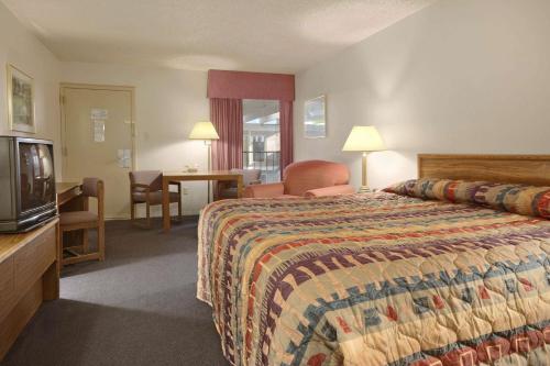 a hotel room with a bed and a television at Ramada by Wyndham Sterling in Sterling