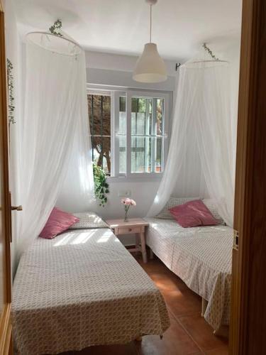two beds in a room with white curtains at Playa Antilla Golf in Lepe