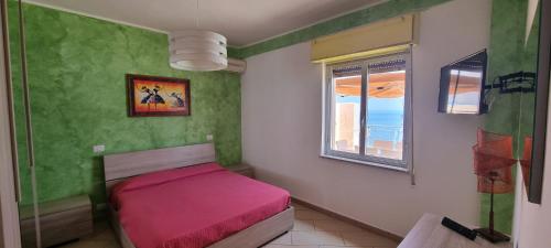 a small bedroom with a pink bed and a window at Cleopatra in Santa Teresa di Riva